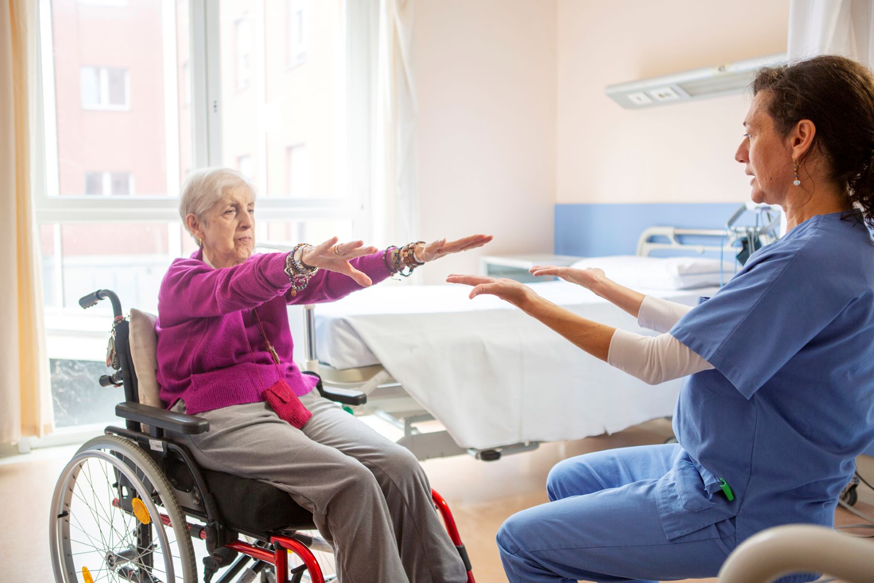 Medico che assiste una paziente anziana nella riabilitazione neuromotoria