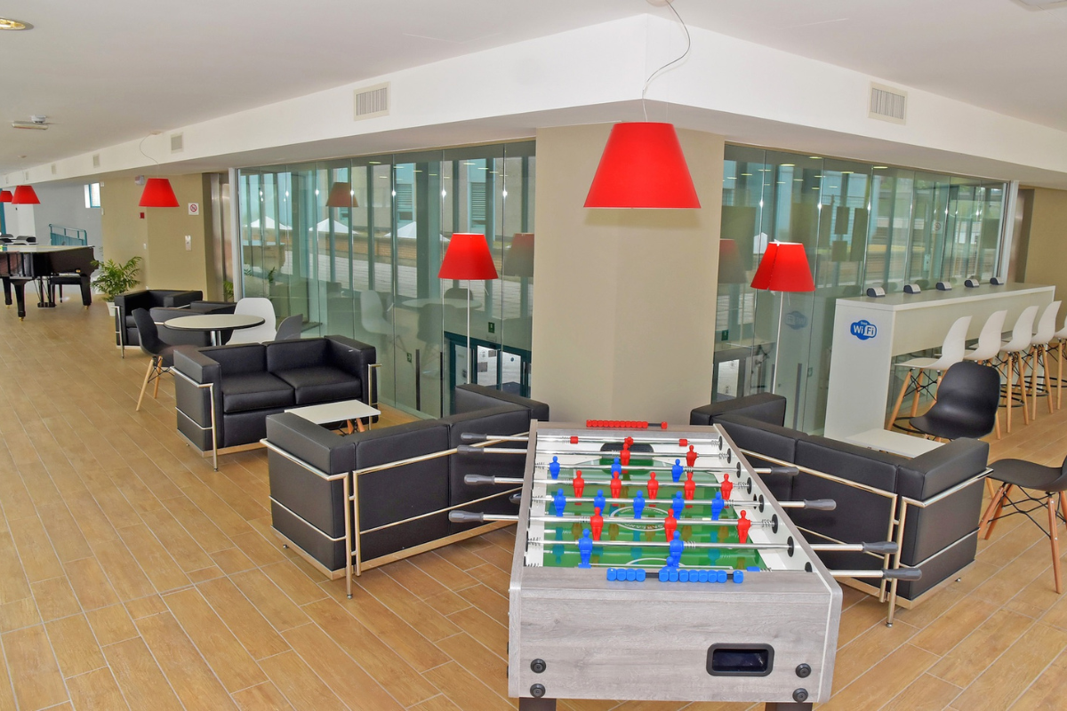 Area lounge dell'IRCCS Maugeri Pavia, composta da tavolini, sedute e un biliardino